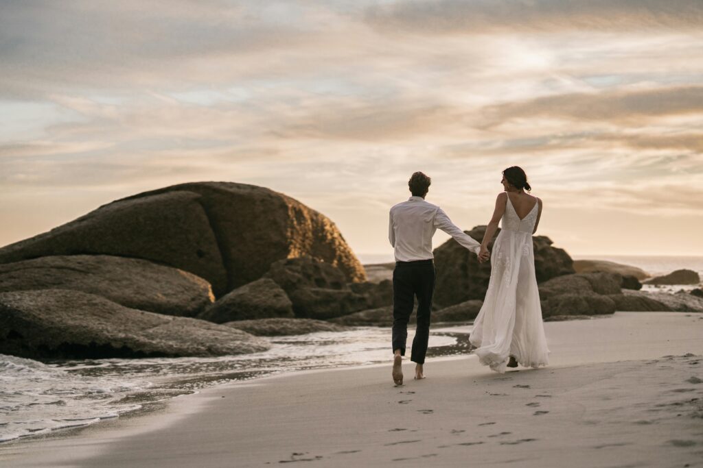newly married couple holding hands while walking on the beach to connect with each other